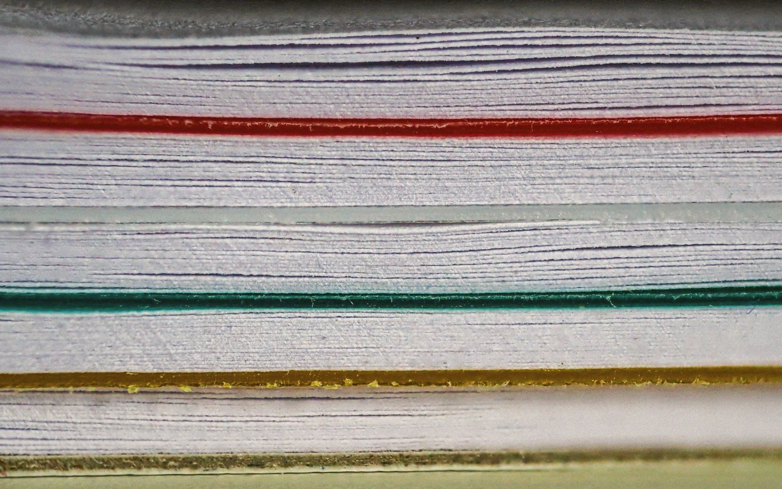 The coloured page edges of a stack of books in close-up